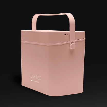 The Rio Lush Box Vanity Case - Large is a minimalist, pale pink beauty storage box with a curved handle, rounded edges, and LUSH BOX on the front, shown against a plain black background.